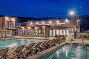 A poolside area with lounge chairs and a building in the background.